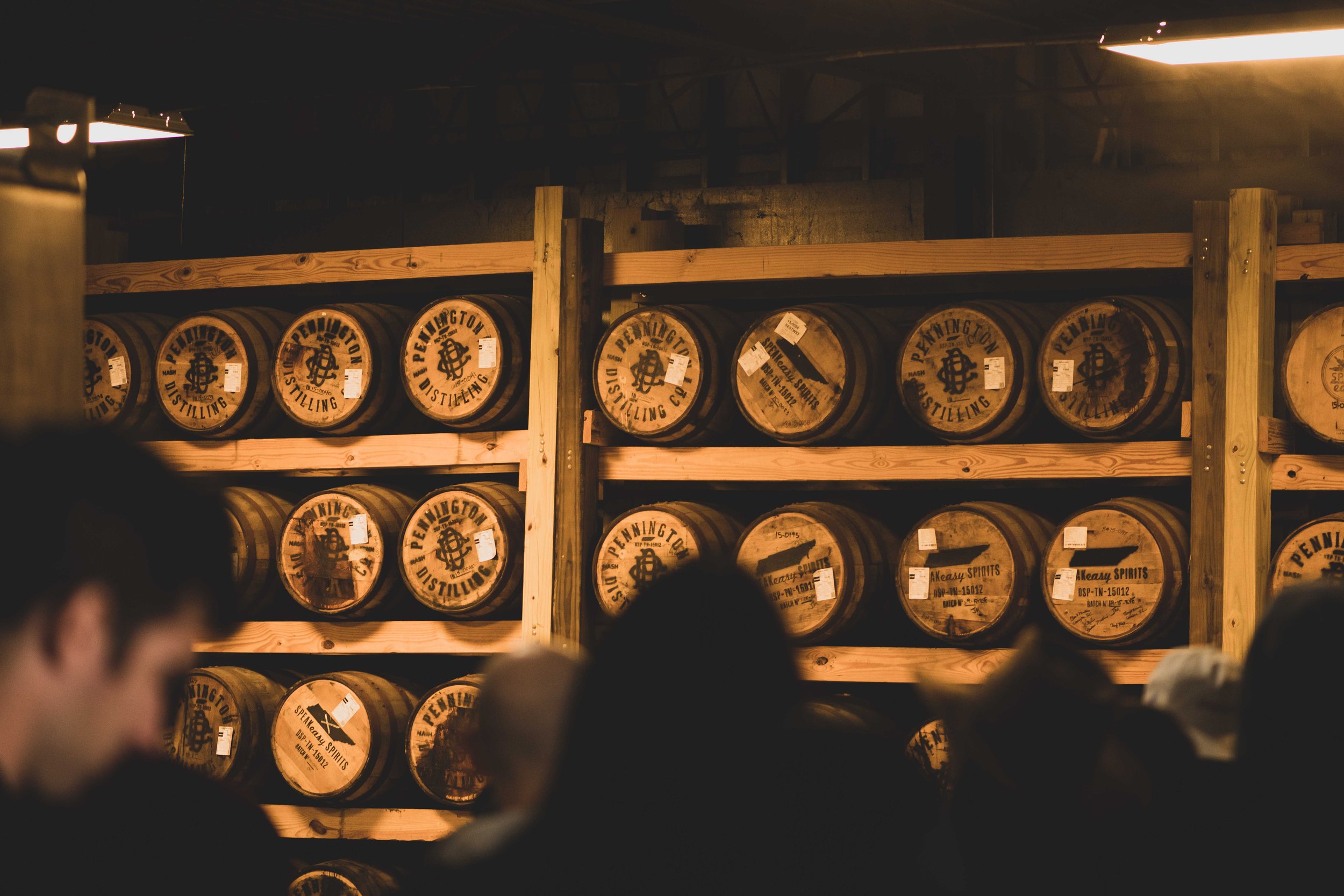 people on a tour of nashville distillery looking at racks of whiskey barrels aging
